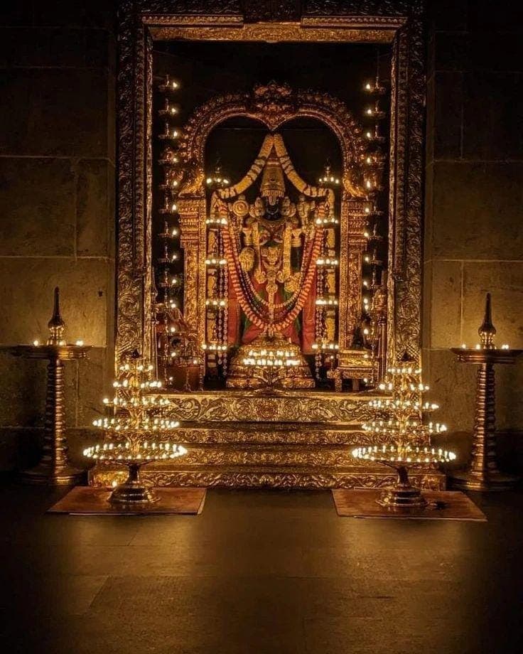 A golden shrine glowing with rows of oil lamps at night